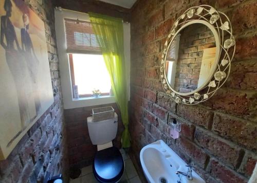 Un baño de ladrillo con lavabo y espejo. en Eagle Falls Country Lodge & Adventures, en Buffelsdrif