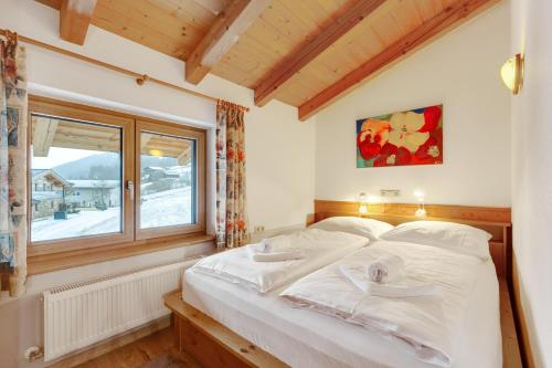 um quarto com uma cama grande e uma janela em Ski in - Ski out Panoramaferienhaus Breitmoos neben Mittelstation em Mittersill