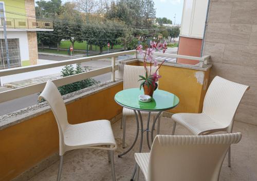 a table and chairs on a balcony with a vase of flowers at Sogno Salento in Guagnano