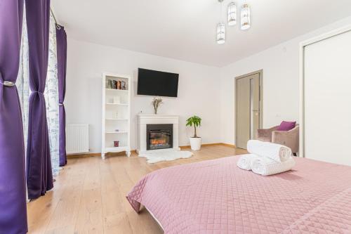 a white bedroom with a bed and a fireplace at Apartamente Lavender Coressi in Braşov