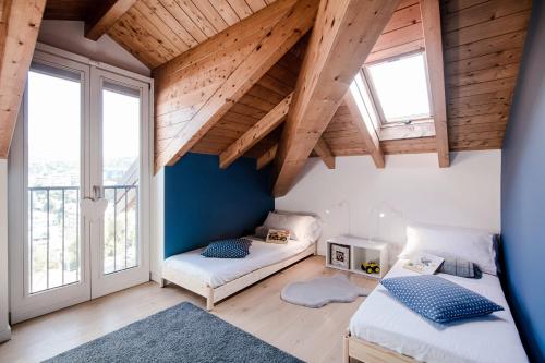 2 letti in una camera con soffitti e finestre in legno di Modern Luxury Attic - byMyHomeInComo a Como
