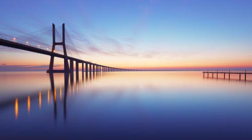 a bridge over a body of water at sunset at Cosy Rooms in Sacavém