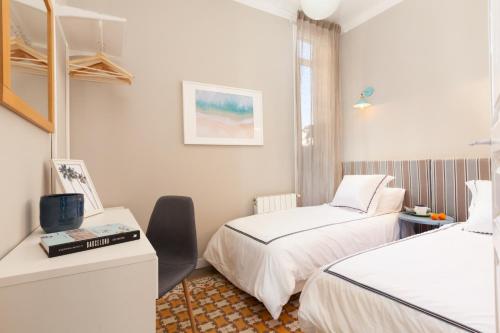 Zimmer mit 2 Betten, einem Schreibtisch und einem Fenster in der Unterkunft My Address on the Beach and Sun in Barcelona