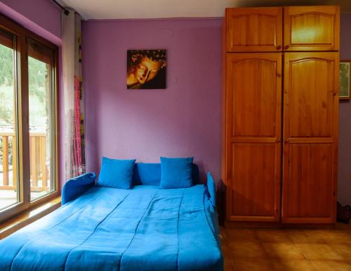 a bedroom with a blue bed and a wooden cabinet at Kione DeuSol in Incles