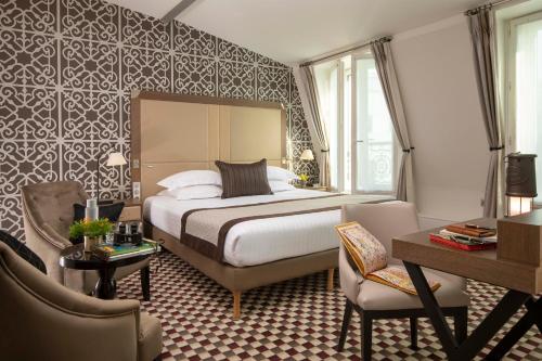 Habitación de hotel con cama, mesa y sillas en Philéas Lazare & Spa, en París