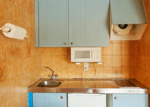 a small kitchen with a sink and a microwave at Kione Lake Placid in Pas de la Casa