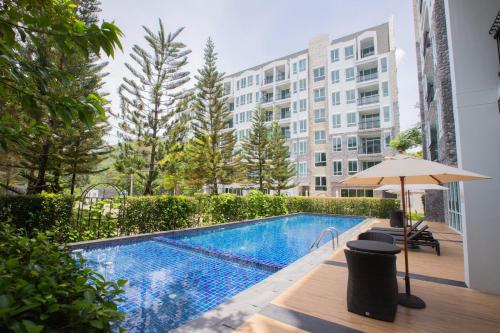 una piscina con sombrilla junto a un edificio en Fortune Courtyard Khao Yai Hotel Official en Mu Si