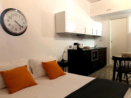 1 cama con 2 almohadas de color naranja y reloj en la pared en Residenza Pedrotti, en Vicenza