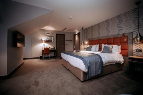 a hotel room with a large bed and a desk at The Tytherington in Macclesfield