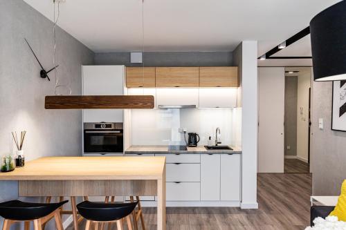 cocina con armarios blancos y mesa de madera en Apartament Bella Vista, en Kielce