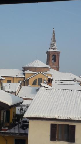 a group of buildings with snowcovered roofs and a clock tower at La Casa sui Tetti in Novi Ligure