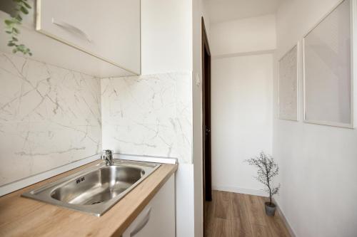 una cucina con lavello in acciaio inossidabile e pareti bianche di WHITE HAVEN - Calea Victoriei Studio a Bucarest