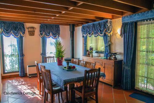 a dining room with a table and chairs and windows at Observatory Cottages in Mount Dandenong