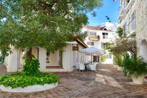 a courtyard with a table and chairs and a tree at 3BR Apt @CadaquesCaribe Bayahibe in San Rafael del Yuma