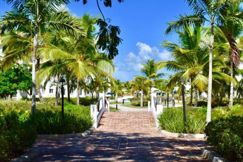 a brick path with palm trees in a park at 3BR Apt @CadaquesCaribe Bayahibe in San Rafael del Yuma
