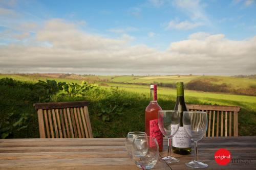 Ein Holztisch mit zwei Flaschen Wein und Gläsern in der Unterkunft Creber Cottage in Totnes