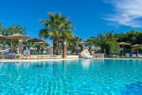 a large swimming pool with chairs and umbrellas at Stamos All Inclusive in Faliraki