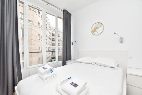 een slaapkamer met een wit bed en een raam bij Appartement qui touche casiment la Bastille ! in Parijs
