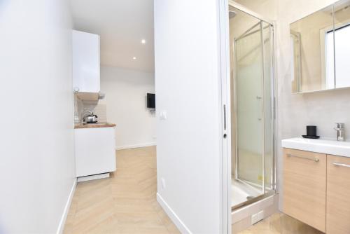 een witte badkamer met een wastafel en een douche bij Appartement qui touche casiment la Bastille ! in Parijs