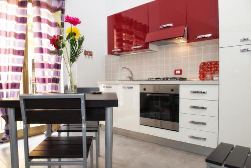 una cocina con armarios rojos y una mesa con un jarrón de flores en Casa Longo 2, en Castellammare del Golfo