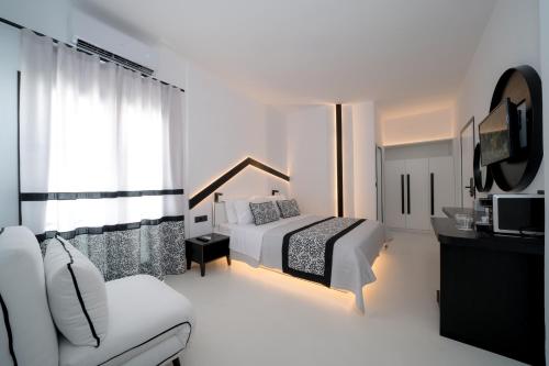 a white bedroom with a bed and a tv at Divelia Hotel in Perissa
