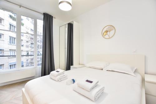 a white bedroom with a large window and a white bed at CMG-Voltaire/ Bastille - D in Paris