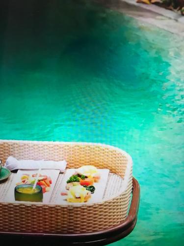 un tavolo con del cibo sopra accanto a una piscina di Villa Athena a Seminyak