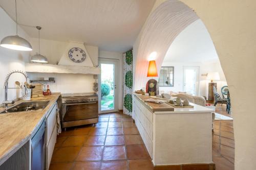 a kitchen with an archway and a large kitchen with a sink at BGItalianVacation - Ville Li Conchi in Castiadas
