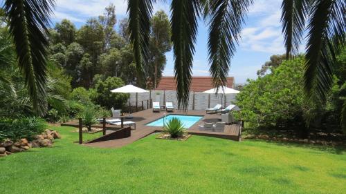 a backyard with a swimming pool and a lawn at Bloemenzee Boutique B&B in Gordonʼs Bay