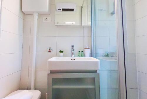 a white bathroom with a sink and a shower at Beachfront Apartment Mala Tereza in Split