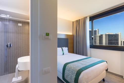 a hotel room with a bed and a bathroom with a window at Holiday Inn Naples by IHG in Naples