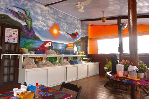 a dining room with a painting of birds on the wall at Beija Flor Pousada in Ubatuba