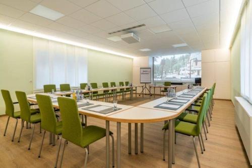 a conference room with a long table and green chairs at Stolberger Hof in Stolberg i. Harz