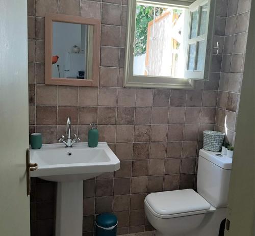 een badkamer met een wastafel, een toilet en een spiegel bij Lemon Garden house near the sea in Lagonissi