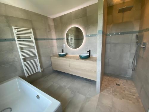 un bagno con vasca, lavandino e specchio di Vue mer Bretagne Villa d'architecte a Plérin