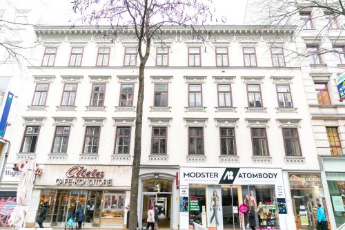 維也納的住宿－Mariahilfer Boutique Rooms - Virtual Reception & Self-Checkin，一条拥有商店的城市街道上的白色大建筑