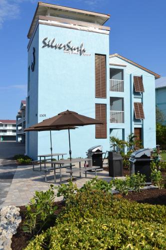 a building with tables and an umbrella in front of it at Silver Surf Gulf Beach Resort in Bradenton Beach