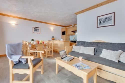 een woonkamer met een bank en een tafel met een laptop bij Residence Chalet de l'Adonis in Les Menuires