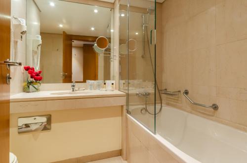 a bathroom with a shower and a sink and a tub at Hotel Marques De Pombal in Lisbon