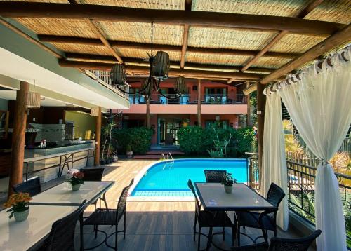 an outdoor patio with tables and a swimming pool at Pousada Arraial Charme in Arraial d'Ajuda