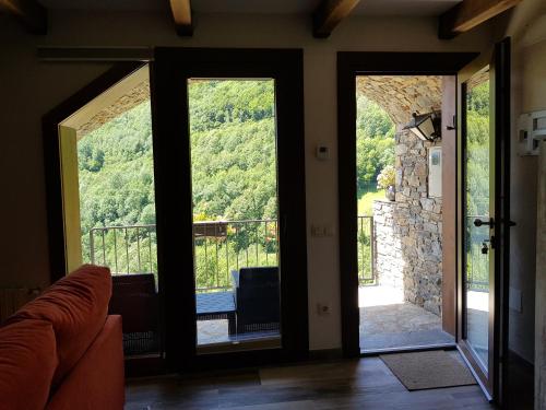 a living room with doors open to a balcony at Can Batlló, entorno acojedor y romántico in Molló