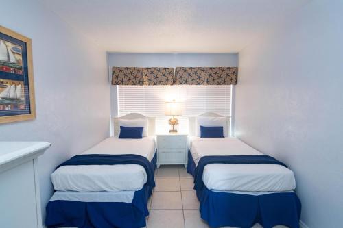 two beds in a small room with a window at Ocean Beach Club in New Smyrna Beach