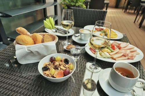 a table with plates of food and glasses of wine at Imola Hotel Platán in Eger