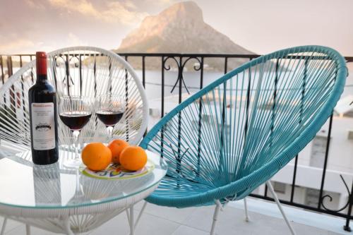 a table with two glasses of wine and oranges on a balcony at Calma apartment in Masouri