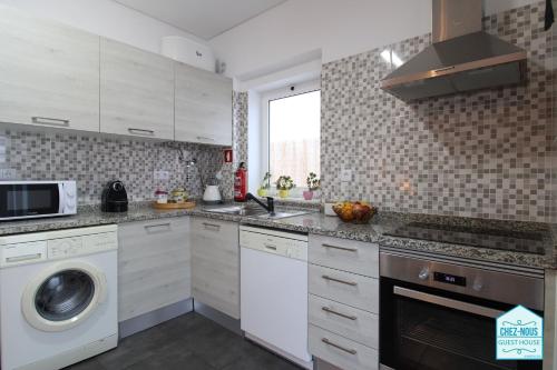a kitchen with white cabinets and a washer and dryer at Chez Nous - Guest House in Barreiro