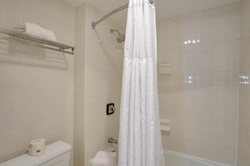 a bathroom with a shower with a white shower curtain at The Clarkson Inn in Potsdam