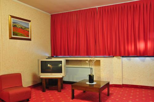 a hotel room with a red curtain and a tv at Hotel Country Club in Capannori