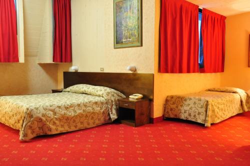 a hotel room with two beds and red curtains at Hotel Country Club in Capannori