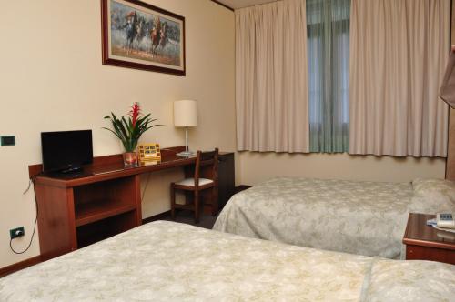 a hotel room with two beds and a desk with a computer at Hotel Country Club in Capannori
