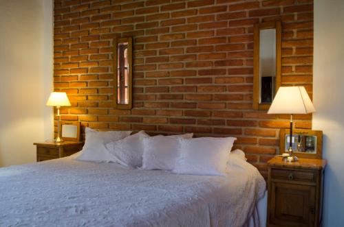 a bedroom with a white bed with a brick wall at Quebrada Mansa in Nono